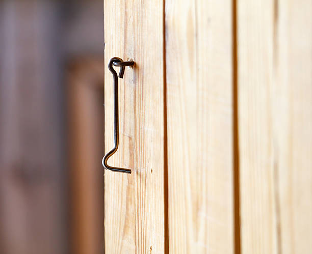 A wooden door with a metal latch. The latch is bent and has a hook on it. The door is open