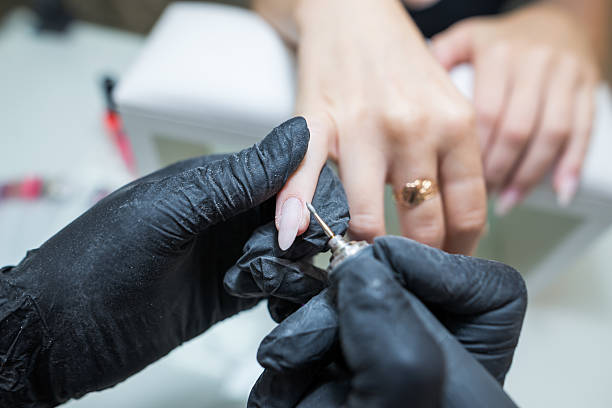 istock Beauty salon, manicure. Professional hardware manicure using an electric machine in a beauty salon. the master uses an electric machine to remove the cuticle 2233468991