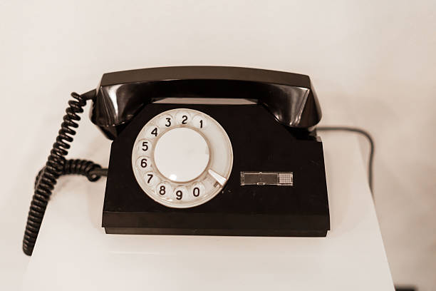 istock A classic black rotary phone is positioned on a white table, capturing the retro charm of mid-20th century design in a bright and airy space 2233469876