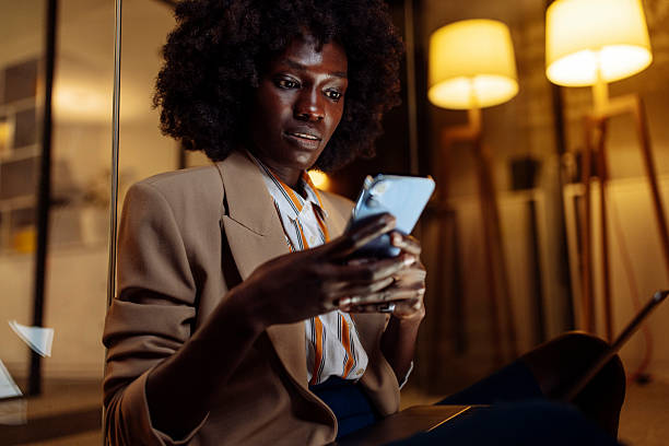 istock Professional Woman Using Smartphone in Modern Office Environment at Night 2233470129