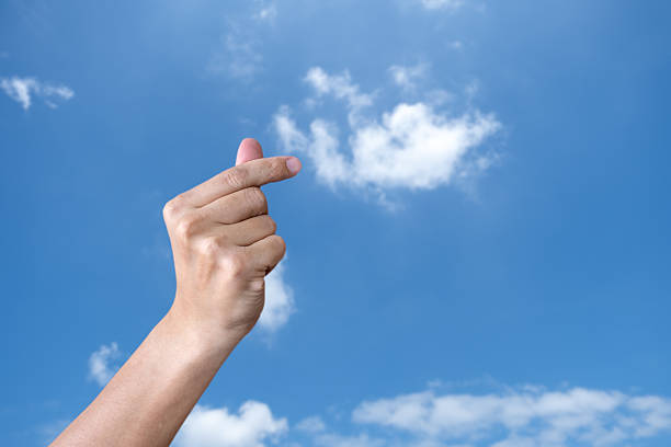 Boy's hand holding a paper aeroplane against a blue sky. Space for copy.