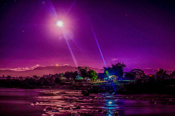 A full moon casts a violet glow over the Philippine countryside, with a bright beam of light cutting through the night sky as it reflects on a river below—an ethereal scene capturing the stillness of rural life under the stars. Photo: Edd Castro
