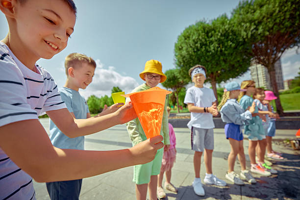 istock Water relay. Children playing games in park on a sunny day 2233473849