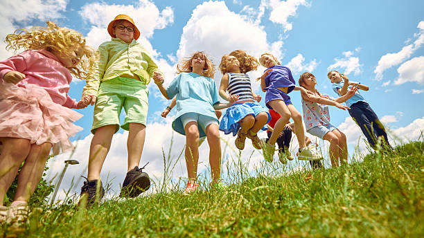 istock Children jumping in grassy field under summer sky 2233473874