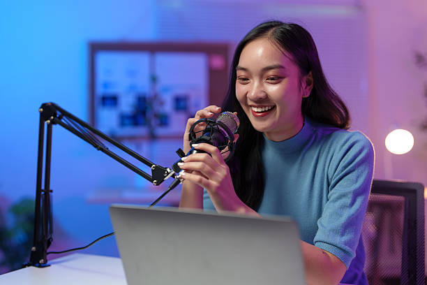 istock Happy creator speaking into a microphone while recording engaging audio content on a laptop in a vibrant, colorful home studio, radiating creativity and inspiration 2233474278
