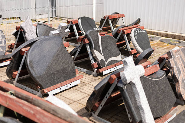 istock Granite gravestones are neatly arranged on display stands in a stone yard. The setting is bright and sunny, highlighting the various designs and textures of the stones 2233474362