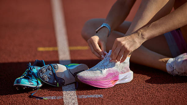 istock Runner tying shoelaces on athletic track with light blue shoes beside 2233475130