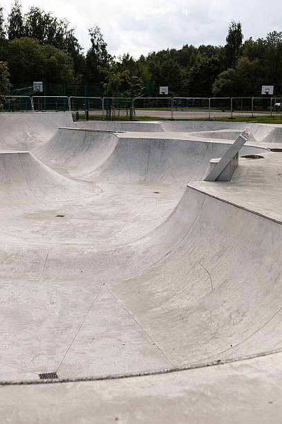 istock A spacious skatepark featuring smooth concrete ramps awaits skaters. The area is surrounded by greenery, with an overcast sky creating a calm atmosphere in the early evening 2233476058
