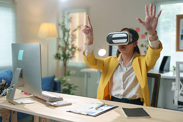istock Businesswoman wearing a vr headset engages with virtual reality while seated at a modern office desk, immersing herself in the metaverse and discovering innovative digital experiences 2233476263