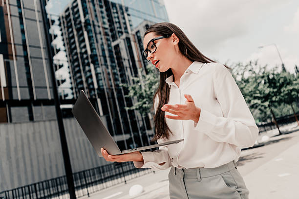 istock Confident professional businesswoman using laptop for work and communication outdoors in a modern urban city setting 2233476457