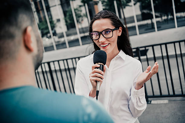 istock Successful female interviewer outdoors holding a microphone engaging in a city street dialogue showcasing communication skills 2233476543