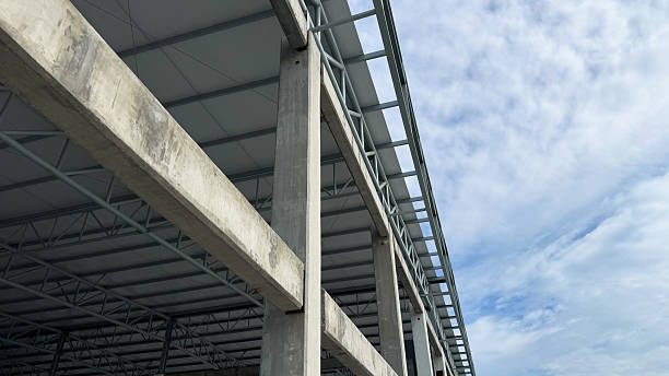 istock Concrete column and horizontal beam connection with steel roof structure, under construction building with modern engineering framework and sky background. 2233477395