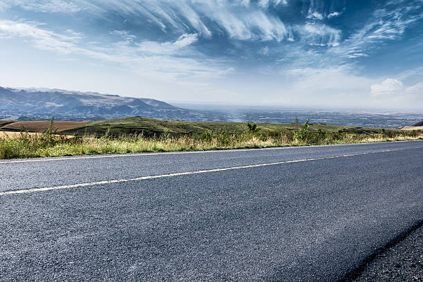 istock Empty asphalt road and distant rolling hills with mountains under blue sky. 2233478777