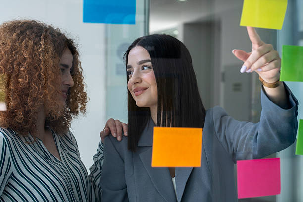 istock Businesswomen planning strategy using sticky notes on glass wall in office 2233480230