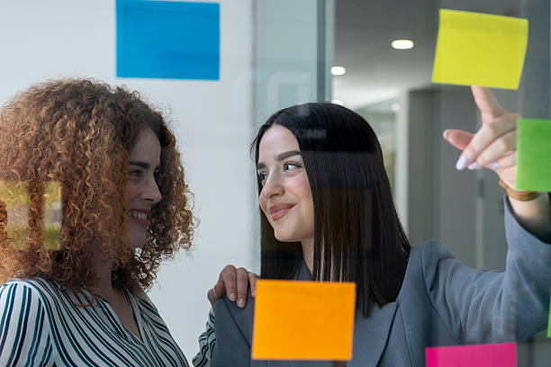 istock Businesswomen planning strategy using sticky notes on glass wall in office 2233481239