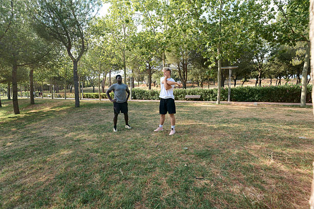 istock Two young men stretching together before exercising outdoors in a park 2233481576