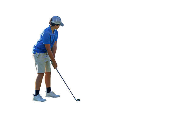 Young male golfer wearing a blue shirt and beige shorts takes a shot with his golf club on a white background, focused on perfecting his swing and drive