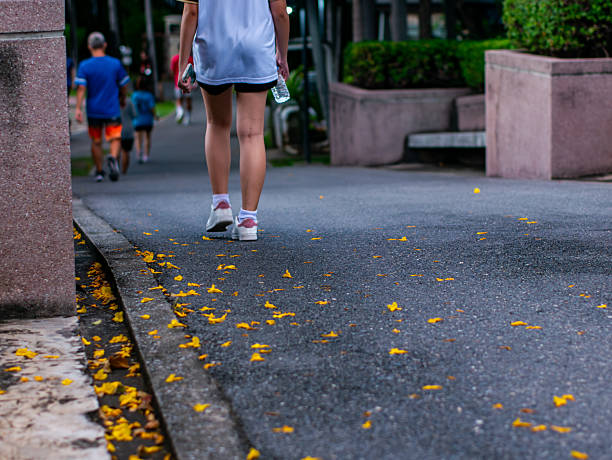 Lifestyle Health care. Asian woman jogging on the street in the evening park with a warm and relaxing environment. People jog for strength. Relaxation and exercise to refresh. close up legs running