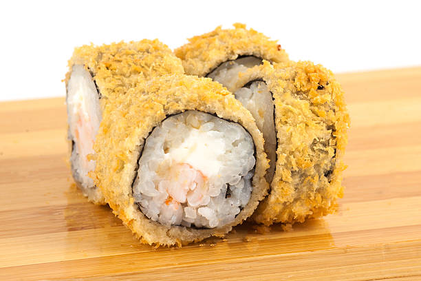 istock Delicious Crispy Fried Sushi Rolls Arranged on a Wooden Board 2233484166