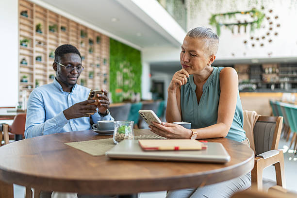 istock Business people using mobile phones during coffee break 2233485925