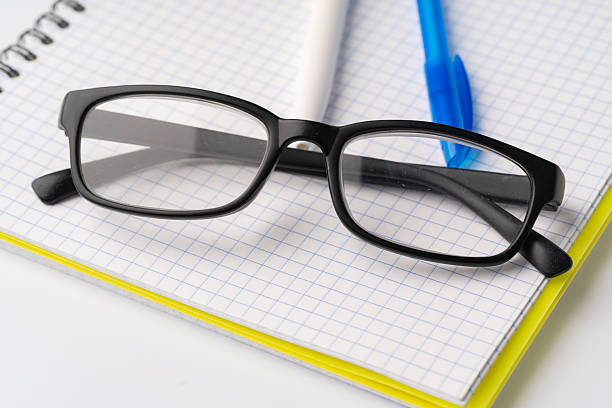 istock Two pens and glasses on open notepad, close up 2233485942