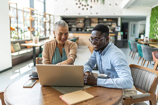 istock Smiling business people working on laptop in cafe 2233486728