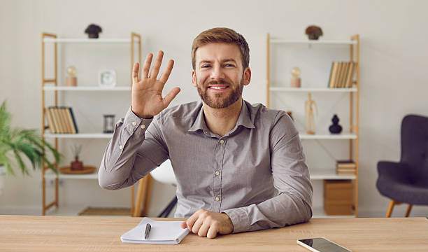 istock Businessman having video call looking at webcam waving his hand in greeting 2233486741