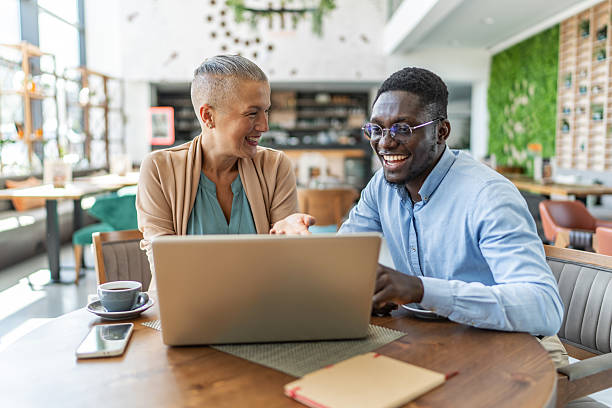 istock Smiling business people working on laptop in cafe 2233486762