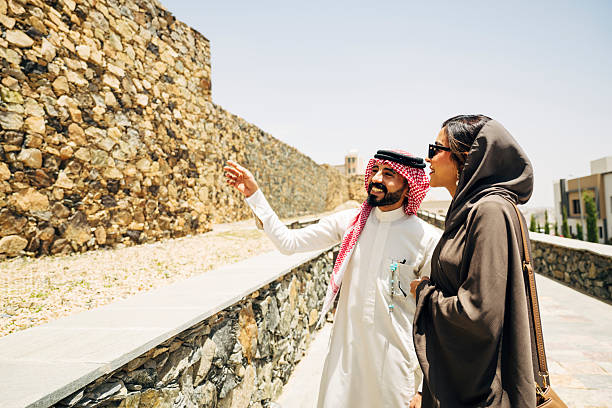 Middle Eastern couple touring Saudi Arabia enjoy local landmark Shamsan Ottoman Castle