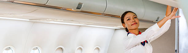 istock Flight attendant in uniform checks overhead bin in modern airplane cabin, assisting passenger during boarding. Aircraft interior shows aisle, airline travel, and in-flight service professionalism. 2233491777