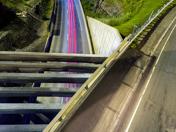 Nighttime view of elevated roads and bridge, showcasing light trails from passing vehicles, emphasizing modern infrastructure and transportation.
