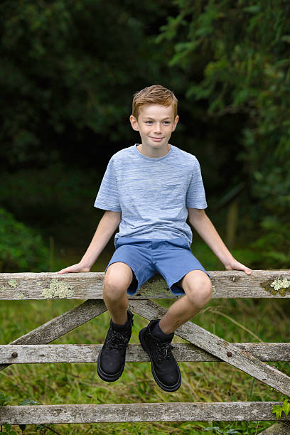 istock Boy of 10 sitting on a farm gate 2233494430