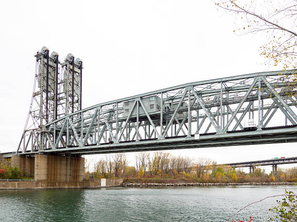 istock Industrial Bridge Spanning Over Calm River on an Overcast Autumn Day 2233494538