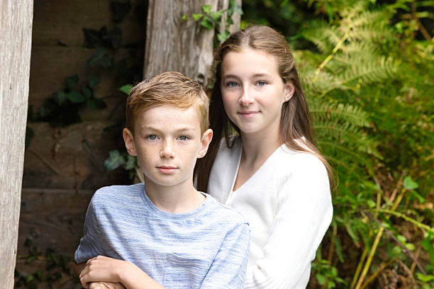 Siblings leaning on the gate of a disused stable. Focus on boy.