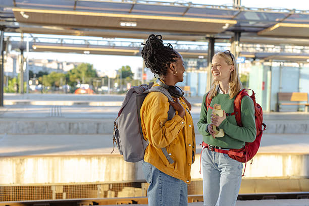 istock Two friends chatting at a train station platform on a sunny day 2233495621