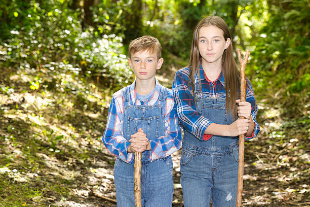 Two happy girls in casual clothing walking in woods during sunny day