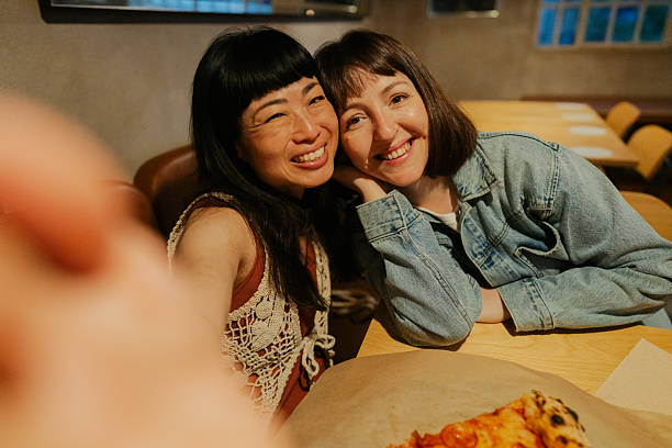 istock Female friends capturing a selfie while eating out in a pizza place 2233496307