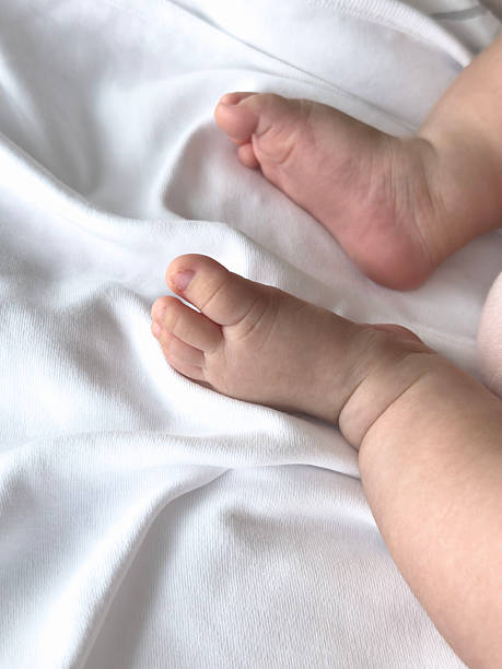 istock Chubby newborn baby feet resting on soft white cotton blanket 2233496431