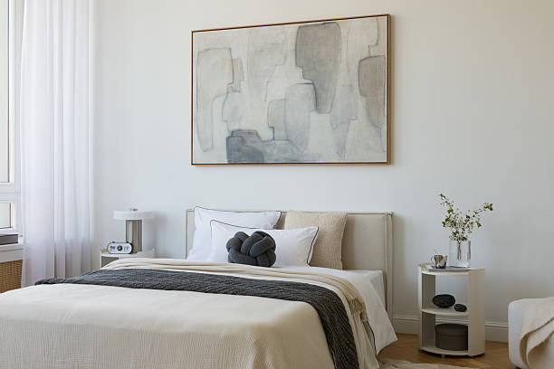istock Stylish compositions of bedroom with soft lighting, layered textiles, decorations and abstract wall art. Neutral tones and quiet elegance. 2233500557