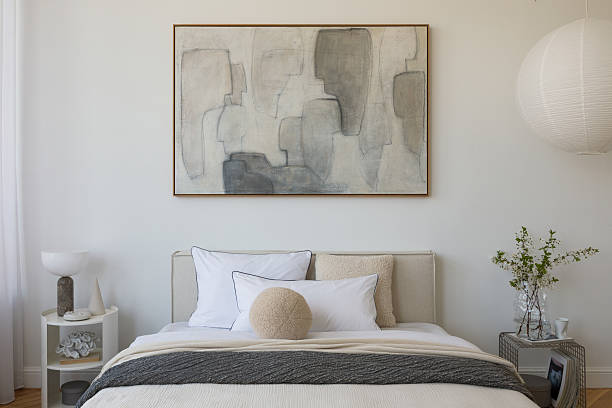 istock Stylish compositions of bedroom with soft lighting, layered textiles, decorations and abstract wall art. Neutral tones and quiet elegance. 2233500569