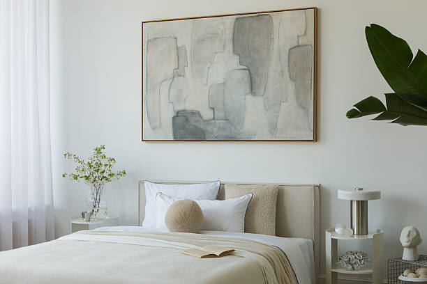 istock Stylish compositions of bedroom with soft lighting, layered textiles, decorations and abstract wall art. Neutral tones and quiet elegance. 2233500570