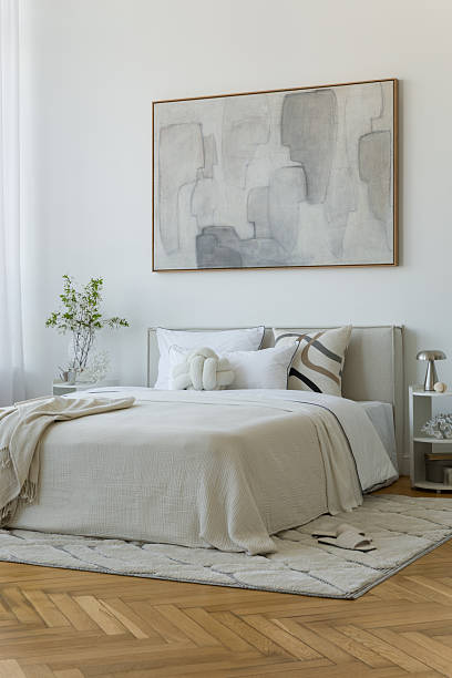 istock Stylish compositions of bedroom with soft lighting, layered textiles, decorations and abstract wall art. Neutral tones and quiet elegance. 2233500612