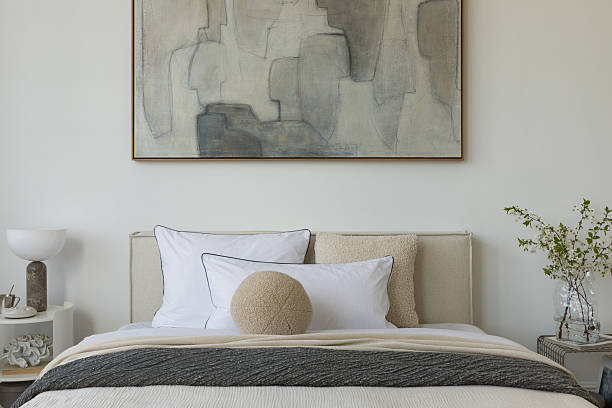 istock Stylish compositions of bedroom with soft lighting, layered textiles, decorations and abstract wall art. Neutral tones and quiet elegance. 2233500641