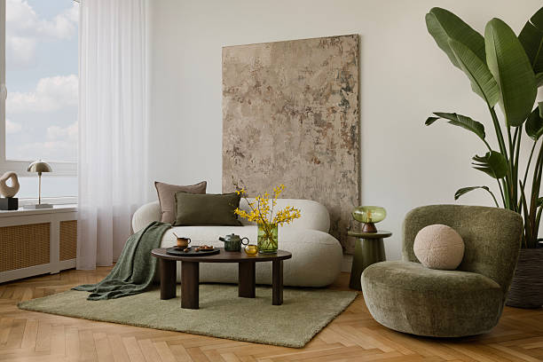 istock Light-filled interior with white curved sofa, abstract textured mock up wall art and green velvet lounge chair with soft round cushion. 2233501428