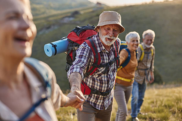istock Happy senior hikers cooperating while moving up the hill. 2233502522