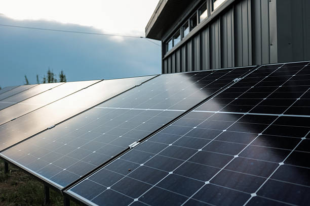 istock Solar panel installations beside a modern utility building in a green field, generating renewable energy on a sunny day 2233504090