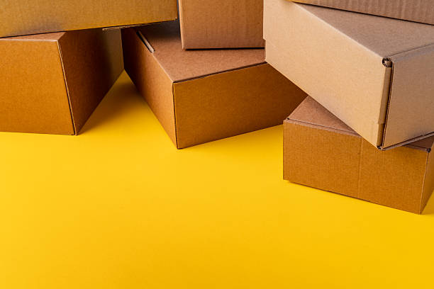 istock Beige cardboard boxes on yellow background, close up 2233504092