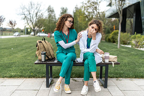 istock Young doctor consoling sad colleague sitting on bench 2233504500