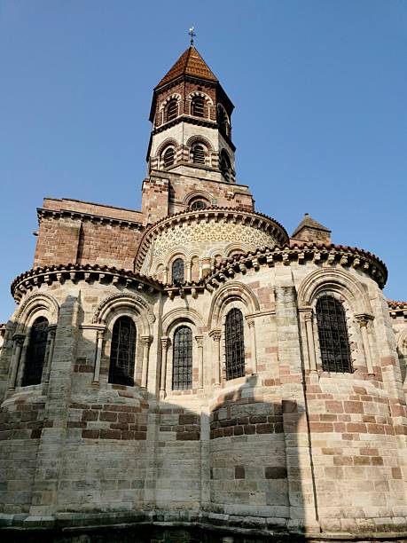 Historic Romanesque church with intricate stonework and a tall bell tower against a clear blue sky, showcasing architectural beauty.