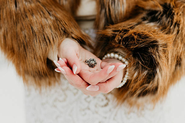 Close-up of a woman holding a vintage ring in her hands, wearing a fur coat and lace dress. Perfect for luxury branding, fashion magazines, jewellery marketing, and editorial wedding content.